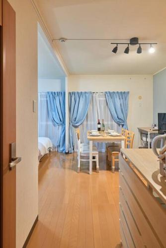 a kitchen and dining room with a table and blue curtains at Westeria202 JR春日井駅徒歩3分ペット連れ長期滞在可能 in Kasugai