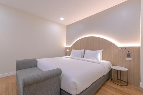 a bedroom with a large white bed and a chair at Shewin de Bangkok in Ban Bang Bamru