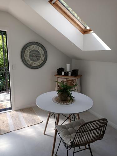 a table and chairs in a room with a clock on the wall at Beach Getaway Studio Matakatia/Tindalls in Whangaparaoa