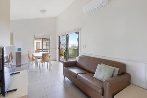a living room with a couch and a dining room at Reflections Bermagui - Holiday Park in Bermagui