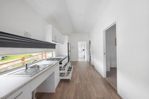 a white kitchen with a sink and a counter at Reflections Bermagui - Holiday Park in Bermagui