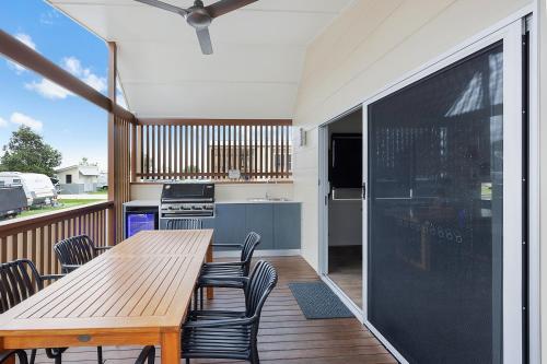 a patio with a wooden table and chairs on a deck at Reflections Bermagui - Holiday Park in Bermagui
