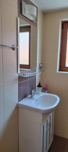 a bathroom with a white sink and a mirror at Anchors Guest House in Sozopol
