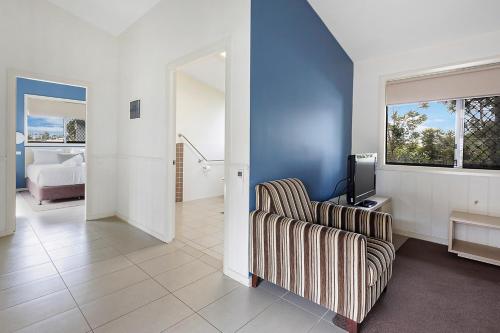 a living room with a chair and a television at Reflections Bermagui - Holiday Park in Bermagui
