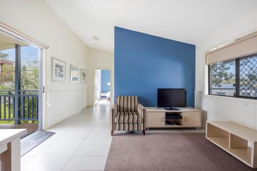 a living room with a blue wall and a chair at Reflections Bermagui - Holiday Park in Bermagui