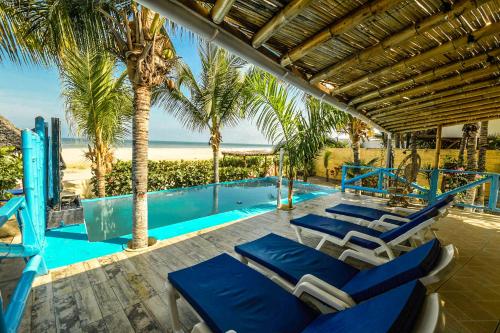 een patio met stoelen en een zwembad met palmbomen bij Casa Estrella de Mar in Zorritos