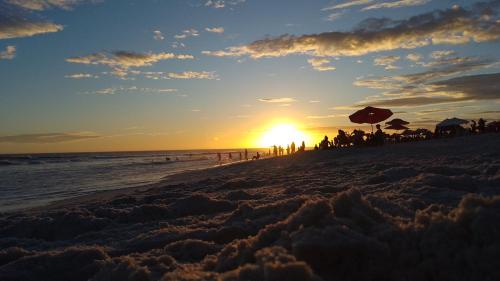 a group of people on the beach at sunset at Golden Lake Apart Hotel Arraial do Cabo RJ A&J 2 in Arraial do Cabo