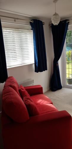 - un canapé rouge dans le salon doté d'une fenêtre dans l'établissement Greenway, à Ollerton