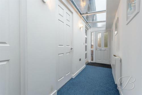 un couloir avec une porte en verre et un tapis bleu dans l'établissement Greenway, à Ollerton