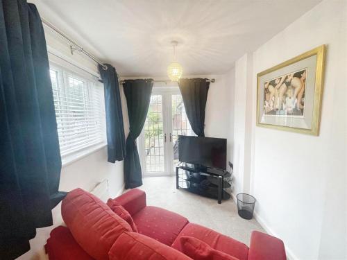 a living room with a red couch and a television at Greenway in Ollerton