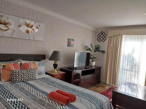 a bedroom with a bed with red pillows and a television at Sweet Home by the Golf Course in Canberra