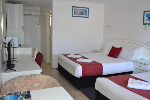 a hotel room with two beds and a television at Calico Court Motel in Tweed Heads
