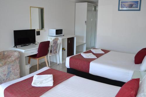 a hotel room with two beds and a desk with a computer at Calico Court Motel in Tweed Heads