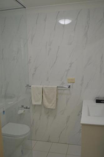a white bathroom with a toilet and a sink at Calico Court Motel in Tweed Heads