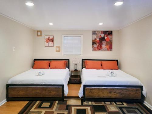 um quarto com 2 camas com almofadas laranja em Haven Place em Alexandria