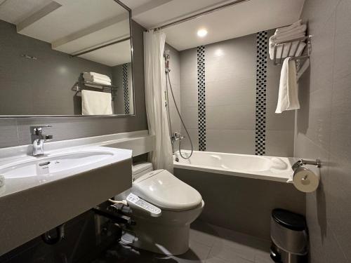 a bathroom with a sink and a toilet and a tub at 銀座飯店Ginza Hotel in Taipei