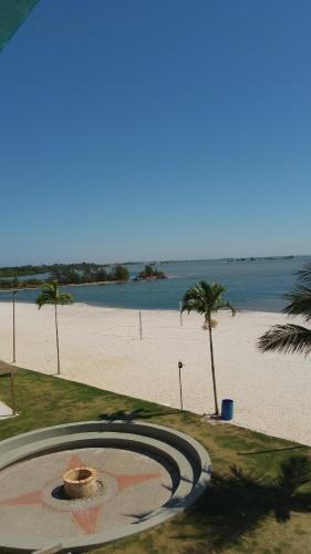 a view of a beach with palm trees and the ocean at Golden Lake Apart Hotel Arraial do Cabo RJ A&J 2 in Arraial do Cabo