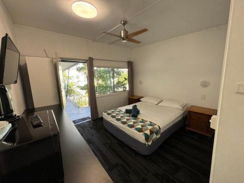 1 dormitorio con 1 cama y ventilador de techo en Cairns City Motel, en Cairns