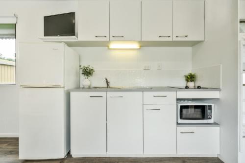 a white kitchen with white cabinets and a microwave at Tasman Holiday Parks - Hervey Bay in Hervey Bay