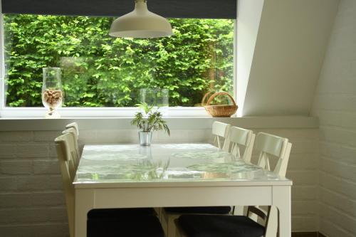 een witte tafel en stoelen in een kamer met een raam bij 't Kabouterhuisje (Rekem - Lanaken) in Lanaken