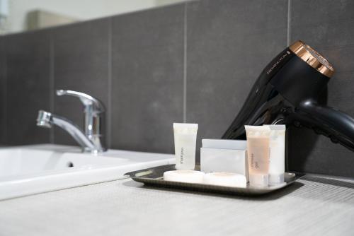 a bathroom counter with a blow dryer and three candles at Bridges on Argyle in Traralgon