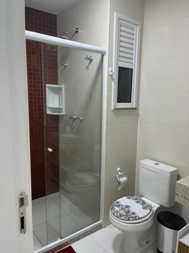 a bathroom with a toilet and a glass shower at Golden Lake Apart Hotel Arraial do Cabo RJ A&J 2 in Arraial do Cabo