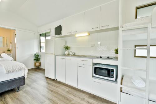 a kitchen with white cabinets and a bed in a room at Tasman Holiday Parks - Hervey Bay in Hervey Bay