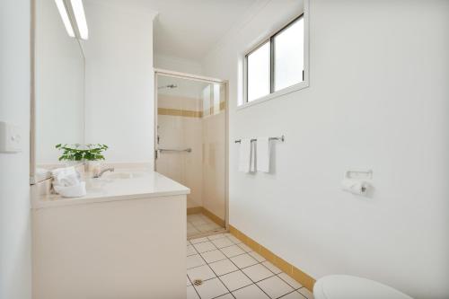 a white bathroom with a shower and a sink at Tasman Holiday Parks - Hervey Bay in Hervey Bay