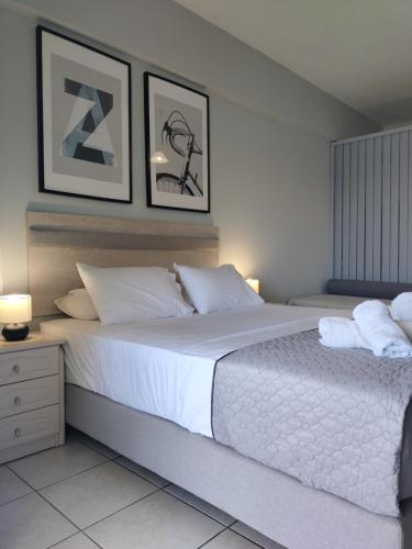 a bedroom with a large white bed with two pictures on the wall at Captain Nick Aparthotel in Mikros Gialos