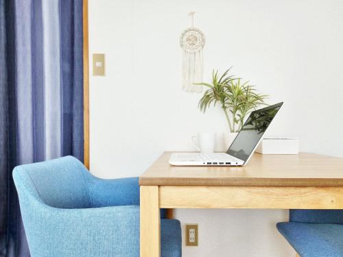 einen Laptop auf einem hölzernen Schreibtisch mit einem blauen Stuhl in der Unterkunft Whole house rental 一棟貸切宿 "Your Home Tottori" 市内中心地近くの素敵な一軒家 in Tottori