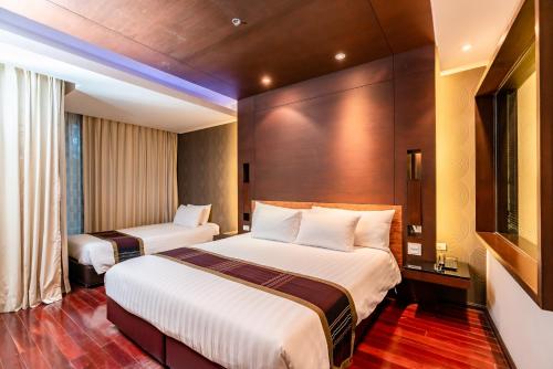a hotel room with two beds and a window at Tara Mantra Cha-Am Resort in Cha Am