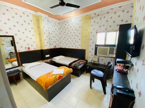 - une chambre avec un lit, un bureau et une télévision dans l'établissement Hotel Regard, à Varanasi