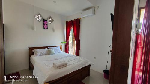 Schlafzimmer mit einem Bett mit weißer Bettwäsche und einem Fenster in der Unterkunft Jatisela Homestay5 in Midang