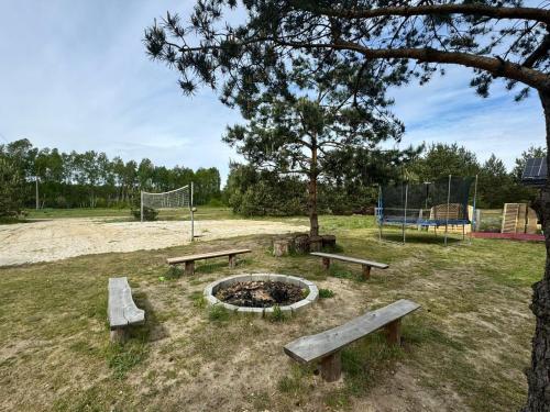 un parc avec des bancs et un foyer extérieur avec un terrain de volley-ball dans l'établissement Domki wypoczynkowe LAS, à Śliwice