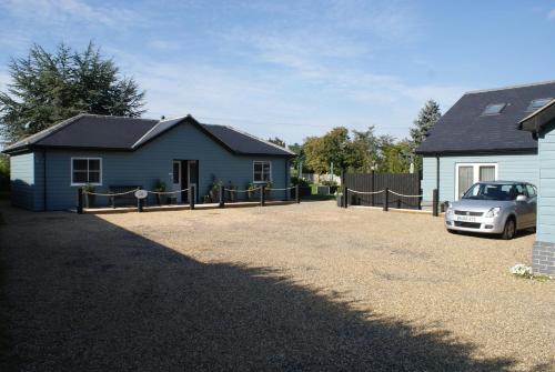 a house with a car parked in front of a driveway at Tirah Guest House in Aldeburgh