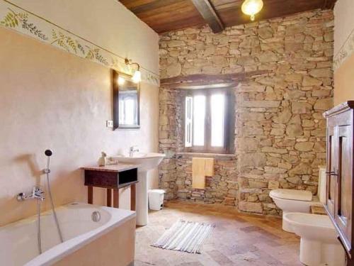La salle de bains aux murs de pierre est pourvue d'une baignoire et d'un lavabo. dans l'établissement Holiday house with pool exclusive use, à Magnano