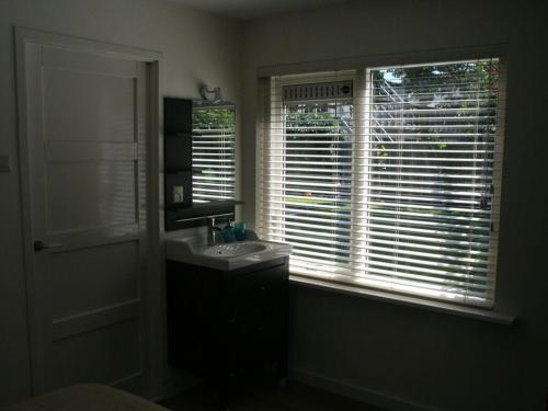 a bathroom with a sink and a window with blinds at Muijs Comfortable holiday residence in Huisduinen