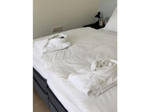 a bed with white sheets and towels on it at Muijs Comfortable holiday residence in Huisduinen
