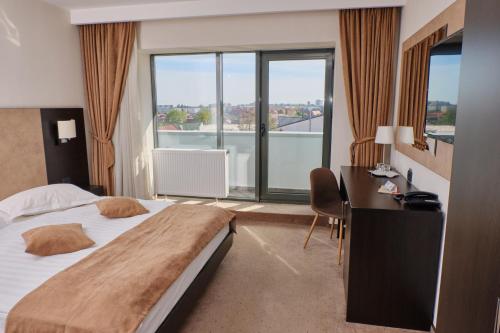 a hotel room with a bed and a desk and a window at Hotel Regal in Braşov