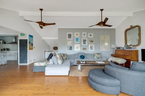 a living room with a blue couch and a piano at Stylish Beach Home - Moments from Water in Terrigal