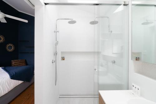uma casa de banho com uma cabina de duche em vidro e uma cama em Stylish Beach Home - Moments from Water em Terrigal