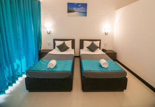 two beds in a room with blue curtains at Aloha Holiday Resort in Baga