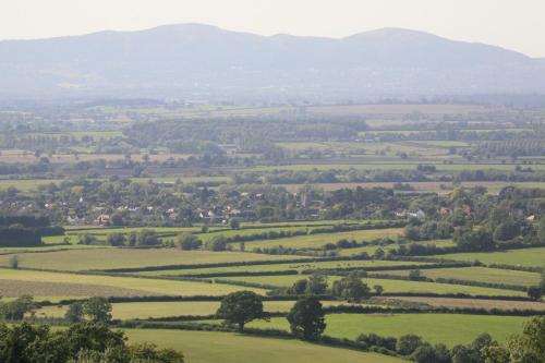 a view of a green field with mountains in the background at Eckington Manor in Pershore