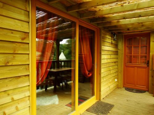 a sliding glass door of a wooden house with a table at Etangs du Moulin in Suzy