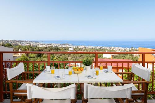 a table on a balcony with a view of the ocean at More Crete Village House Koutouloufari in Hersonissos