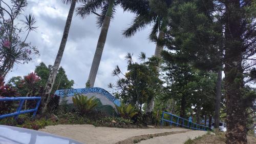 a sign in the middle of a park with palm trees at Island Skyview Resort - JVR by Hiverooms in Balamban