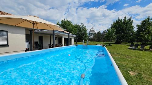 uma piscina com um guarda-sol ao lado de uma casa em Capo House em Gračišče