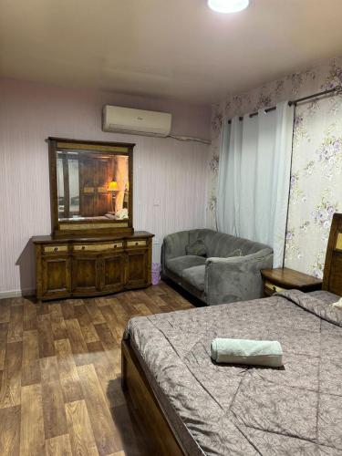 1 dormitorio con cama, sofá y espejo en العين الهيلي مصباح ب 9 en Al Ain