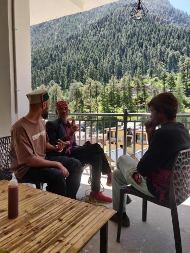 a group of people sitting around a table on a porch at Himtrek Stays, Kasol in Kasol
