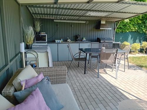 a patio with a couch and a table and a kitchen at Kikapcs apartman in Alsóörs